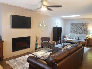 a living room with a leather couch and a flat screen tv at Peachland Lake View Spectacular! in Peachland