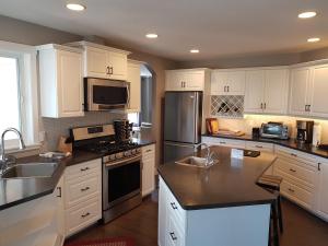 a kitchen with white cabinets and stainless steel appliances at Peachland Lake View Spectacular! in Peachland