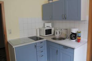 a kitchen with blue cabinets and a sink and a microwave at City-Apartment "royshell" in Güstrow