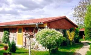 a house with a red roof and a yellow door at Ferienwohnungen am Malchiner See in Bülow