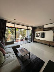 a living room with a couch and a tv at Nai Harn Beach Condo (C2) in Rawai Beach