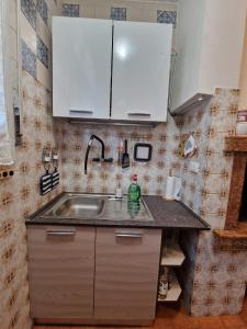 een keuken met een wastafel en witte kasten bij Casa rosario e annamaria in Torri del Benaco +27 foto's