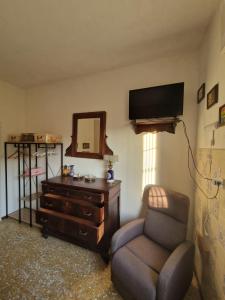 een woonkamer met een stoel, een dressoir en een televisie bij Casa rosario e annamaria in Torri del Benaco