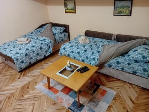 ein Wohnzimmer mit zwei Betten und einem Tisch in der Unterkunft Studio Apartman My Home in Novi Sad
