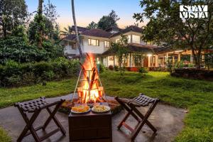 a fire pit in a yard with two chairs at StayVista at Wellbeing Villa in Wayanad