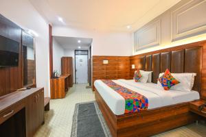 a bedroom with a large bed and a flat screen tv at FabHotel Black Stone Palace in Ghaziabad