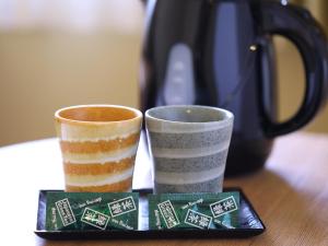 two cups sitting on top of a wooden table at Dormy Inn Express Mikawaanjo in Anjomachi