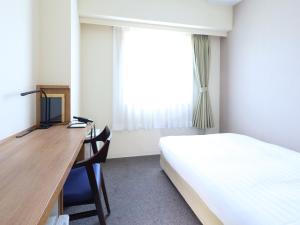 a bedroom with a desk with a bed and a desk at Dormy Inn Express Mikawaanjo in Anjomachi
