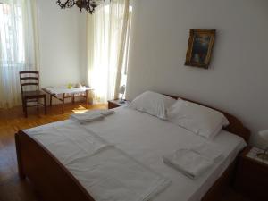 a bedroom with a bed with white sheets and a chair at Inn Town Center in Hvar