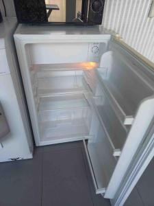 an empty refrigerator with its door open in a kitchen at Studio 76 - Balcon, proche Bâle in Saint-Louis