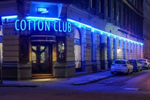 ブダペストにあるコットン ハウス ホテル ブダペストの建物の青ネオンの看板のある店
