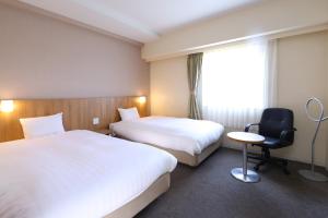 a hotel room with two beds and a chair at Dormy Inn Express Mikawaanjo in Anjomachi