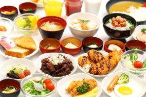 a table with many plates of food in bowls at Dormy Inn Express Mikawaanjo in Anjomachi