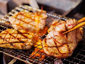 a group of food on a grill with chopsticks at Hotel Monterey Sendai in Sendai