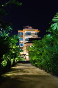 VISA Hotel Hua Hin - SHA Plus في هوا هين: مبنى في الليل مع مسار في الأمام