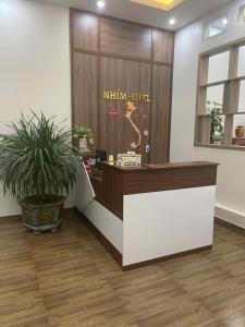 a reception desk in a lobby with a potted plant at Nhím Hotel MC - by BAY LUXURY in Mộc Châu