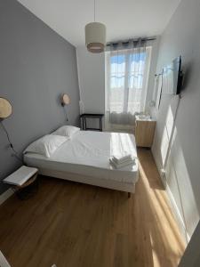 a bedroom with a white bed and a wooden floor at Hotel Clermont Airport in Aulnat +22 photos