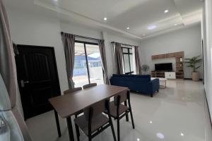 Una sala de estar con una mesa y un sofá azul. en POOMe House, en Hat Yai