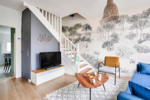 a living room with a tv and a staircase at À 200m de la plage, maison cosy pour 4 in Dinard