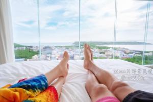 una persona sdraiata su un letto che guarda fuori da una finestra di Moon月行館海景民宿 a Penghu