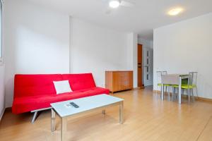 a living room with a red couch and a table at Dorada Apartment Lluna in Calafell +9 photos