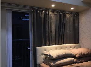 a bed with pillows in front of a window at Cozy 1BR Condo at SM Lights Mandaluyong City in Manila