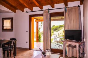 d'un salon avec une télévision et une porte coulissante en verre. dans l'établissement Borgo Arborea Charming Retreat, à Santa Teresa Gallura