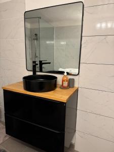 une salle de bain avec un lavabo noir et un miroir dans l'établissement T2 de la Bastide Rouge vue exceptionnelle (180°) sur Aix domaine privé T2 indépendant de 37 m2 avec terrasse exposée plein sud Piscine 10 X 5, à Aix-en-Provence