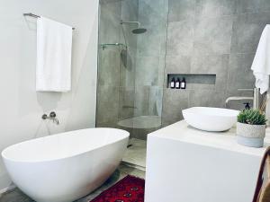 a bathroom with a white tub and a glass shower at Hilltop 39, Oubaai Golf Estate in Herolds Bay