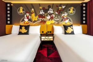ein Zimmer mit zwei Betten und einer Wand mit Mickey-Mouse-Gemälden in der Unterkunft Disney's Hollywood Hotel in Hongkong