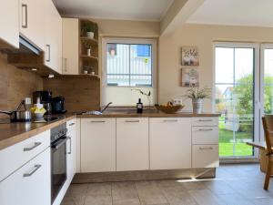 Una cocina con gabinetes blancos y una ventana grande. en Schifferkaten, en Pruchten 21 fotos más