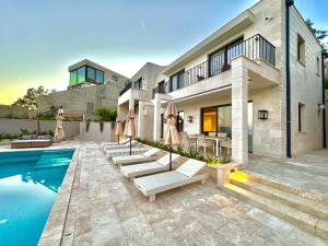 uma casa com piscina com cadeiras e guarda-sóis em Exclusive villa Kaza - Przno em Budva