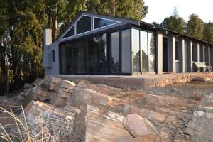una casa en blanco y negro sobre un muro de piedra en Self Catering Unit - Meadow Mist, en Dullstroom