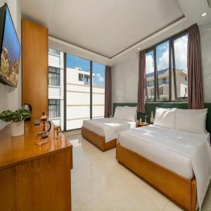 a bedroom with two beds and a flat screen tv at Trang Ngan Hotel by THG in Danang