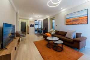 ナイロビにあるKapri Nairobi 2BR Suite w Pool Gym near JKIA SGRのソファと薄型テレビのあるリビングルーム
