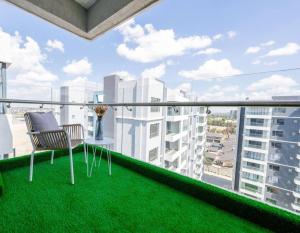 ナイロビにあるKapri Nairobi 2BR Suite w Pool Gym near JKIA SGRのバルコニー(椅子、芝生の上のテーブル付)