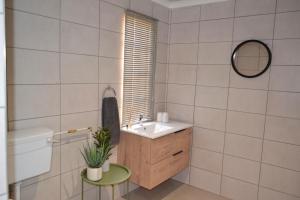 Un baño con lavabo, inodoro y espejo. en Self Catering Unit - Meadow Mist, en Dullstroom