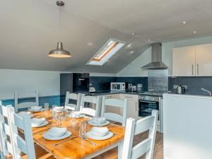 a kitchen with a wooden table and white chairs at Ocean Tide Villa 2 Pets Welcome in Woolacombe