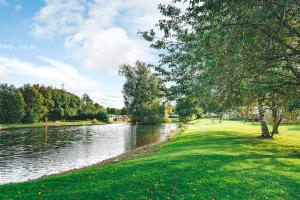 a body of water with trees and grass next to it at Sage Caravan 3 at Riverside Leisure Park in Wooler