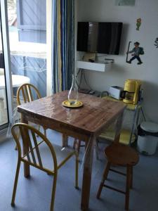 une table en bois avec deux chaises et une télévision dans l'établissement Résidence FACE SUD LA MONGIE, à La Mongie