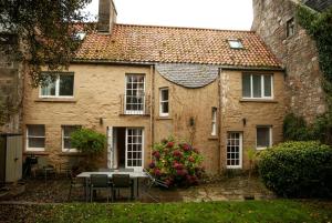 an old house with a table and chairs and flowers at 23 Market Street in St. Andrews