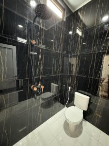 a black tiled bathroom with a toilet and a shower at Griya Tegalweru Palagan Homestay Jogja in Ngaglik