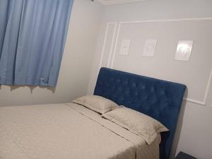 a bed with a blue headboard in a bedroom at apto simples,3min centro, 3 min da Unimed com wifi in Araçatuba