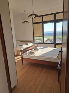 a bedroom with two beds and a large window at Слънчевите Къщи-село Китка in Kitka