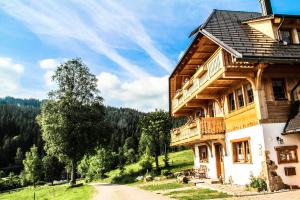 ein großes Holzhaus mit Balkon auf einem Hügel in der Unterkunft Urbanshof Ferienwohnungen in Hinterzarten