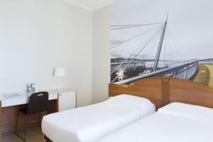 a hotel room with two beds and a desk and a boat at B&B Hotel Pescara in Pescara