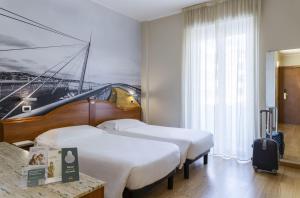 a hotel room with two beds and a painting of a bridge at B&B Hotel Pescara in Pescara