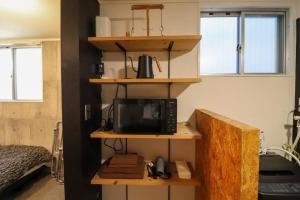 - un four micro-ondes installé sur une étagère dans une pièce dans l'établissement urban stay 今泉, à Susakiuramachi