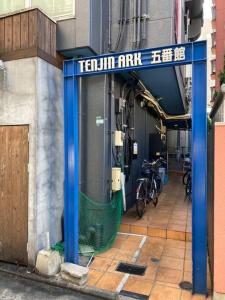 une entrée à un bâtiment avec un panneau bleu dans l'établissement urban stay 今泉, à Susakiuramachi