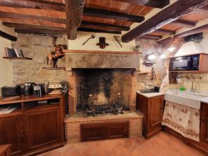 a kitchen with a stone fireplace with a sink at Casa della Rosa in Cortona